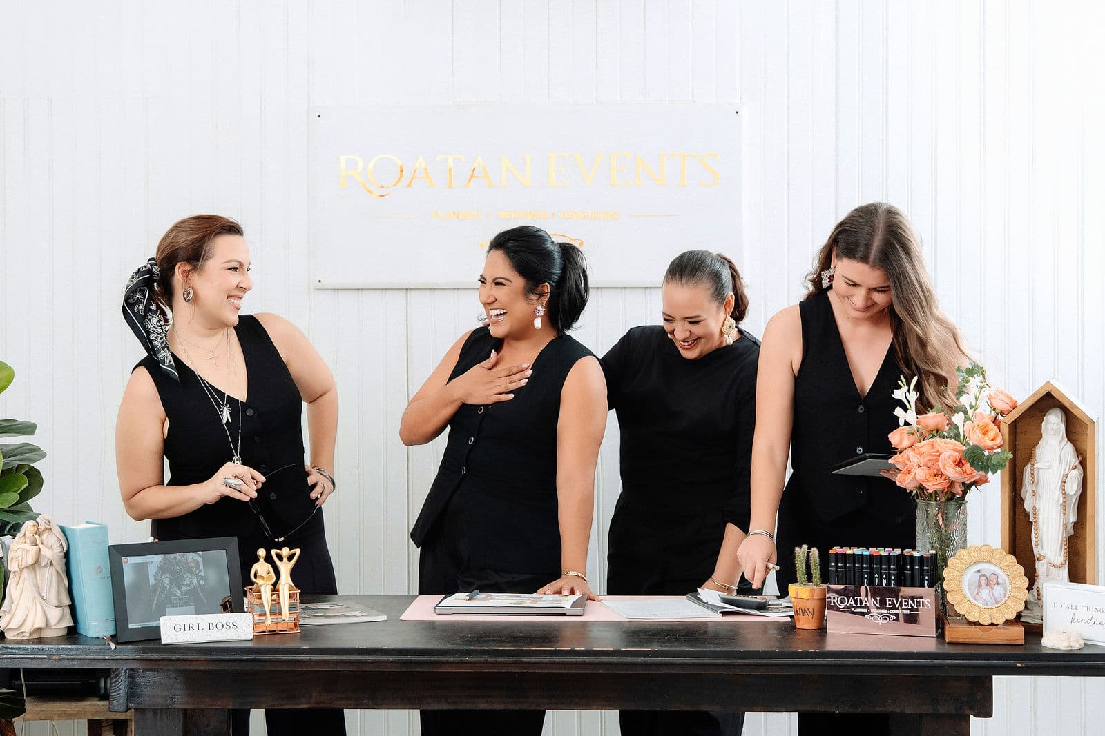 The Roatan Events team laughing together behind their desk in the office